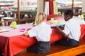 Boy and girl in school uniforms having lunch in school cafeteria Royalty Free Stock Photo