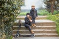 A boy and a girl sit on the steps with a scooter. Royalty Free Stock Photo