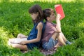 Boy and girl are sitting back-to-back on the lawn in the park and reading books. Royalty Free Stock Photo