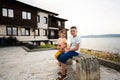 Boy and girl sitting on a bench in front of a house by the sea in Nessebar Royalty Free Stock Photo