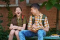 A boy and a girl are sitting on a bench near the school building, they are reading books, the girl is bored, she yawns and wants Royalty Free Stock Photo