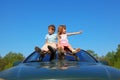 Boy and girl sitting on car roof on sky Royalty Free Stock Photo