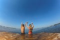 Boy and girl sitting on the edge of a wooden bridge and want to jump into the water Royalty Free Stock Photo