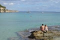 Boy and Girl Sitting on a Rock of Cala Major Beach in Palma de Mallorca, Spain