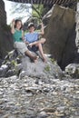 Boy and girl (10-12) sitting on rock throwing stones