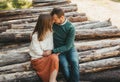 Loving couple sitting on the stack of firewood and logs in the autumn forest. A walk of a couple in love in forest Royalty Free Stock Photo