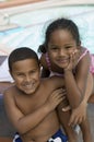 Boy (7-9) and girl (5-6) sitting by swimming pool portrait. Royalty Free Stock Photo