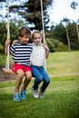 Boy and girl sitting on a swing in park Royalty Free Stock Photo