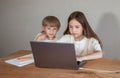 boy and a girl are sitting at a table and looking at a laptop Royalty Free Stock Photo