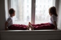 Boy and girl sitting on the windowsill looking out the window