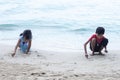 Boy and girl sitting and writing the SOS sign on the sandy beach while going on vacation to the sea. Royalty Free Stock Photo