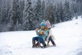 Boy and girl sledding in a snowy forest. Outdoor winter kids fun for Christmas and New Year. Children enjoying a sleigh Royalty Free Stock Photo