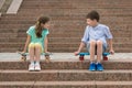 the boy and the girl sort things out, sitting on the steps on the sports boards.