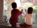 Boy and girl stick New Year`s sticker on the window. Royalty Free Stock Photo