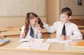 Boy and girl students indulge sitting at a Desk. The boy pulls the girl`s pigtails Royalty Free Stock Photo