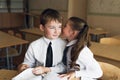 A boy and a girl students sit at a Desk and talk in each other`s ear Royalty Free Stock Photo