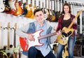 Boy and girl teenagers examining electric guitars