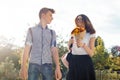 Boy and girl teenagers walking outdoor, couple smiling and talking. Sunny summer day, girl with bouquet of flowers Royalty Free Stock Photo