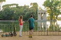 Boy and girl with their push scooters against the backdrop of the Tempio di Esculapio in the park Villa Borghese