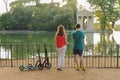 Boy and girl with their push scooters against the backdrop of the Tempio di Esculapio in the park Villa Borghese