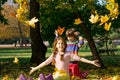 Boy and girl throw yellow leaves up in autumn