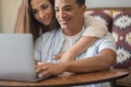 Boy and girl using together a laptop at home sitting and enjoying the web. Young couple interracial people working on computer and Royalty Free Stock Photo