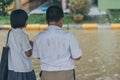 Boy and girl wait to cross flooded street in heavy rainstorm be