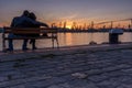 Boy and girl watches the sunset at the sea station with ships. Royalty Free Stock Photo