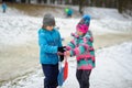 Boy and girl of younger school age in the winter park about slope for toboggans.