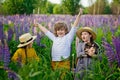 A boy and girls in a hat hold a shepherd puppy in nature in a field with lilac flowers in the background. Tender love for a pet