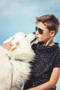 Happy 11 year old boy playing with his dog breed Samoyed at the seashore against a blue sky close up. Best friends rest Royalty Free Stock Photo