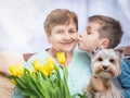 Boy giving a bunch of flowers to grandmother. Grandson and grandma spending, enjoying time together.
