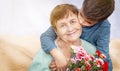 Boy giving a bunch of flowers to grandmother. Grandson and grandma spending, enjoying time together.