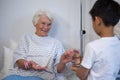 Boy giving a glass of water to senior patient Royalty Free Stock Photo