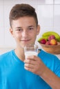 Boy with glass of milk in kitchen