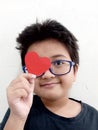 a boy with glasses carrying a red heart