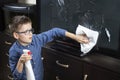 Boy with glasses during cleaning. He wipes the TV screen with dust from the cloth.