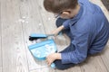Boy in the glasses cleans the flat. He sweeps the paper on the scoop with a brush.