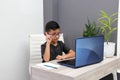 Boy with glasses does home schooling takes online classes at home with a laptop, studies, is surprised and participates in class