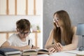 Boy with glasses is hard at work writing his homework. A young tutor helps the student with the lessons. Home schooling Royalty Free Stock Photo