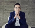 boy with glasses with an intelligent look sits in a chair with his hands clasped in a lock Royalty Free Stock Photo