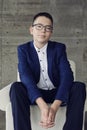 boy with glasses with an intelligent look sits in a chair with his hands clasped in a lock Royalty Free Stock Photo