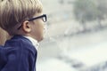 Boy with glasses looks sadly out the window Royalty Free Stock Photo