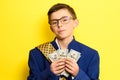 A boy in glasses and an oversized suit with a satisfied face is holding US dollars, a child and big money. Royalty Free Stock Photo