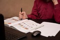 A boy in glasses and a red shirt sits at a black table and does homework, a child in quarantine on distance learning