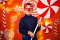 A boy in glasses with reindeer horns and a red nose holds in his hands a large toy candy Royalty Free Stock Photo