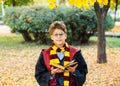 Boy in glasses stands in autumn park with gold leaves, holds book in his hands Royalty Free Stock Photo