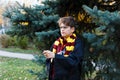 Boy in glasses stands in autumn park with gold leaves, holds wand in his hands. Harry Potter