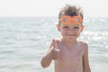 A boy in glasses for swimming shows a thumbs up on the background of the sea. Kid in spectacles for swimming in the sea Royalty Free Stock Photo