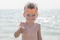 A boy in glasses for swimming shows a thumbs up on the background of the sea. Kid in spectacles for swimming in the sea Royalty Free Stock Photo